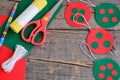 Red and green Christmas balls hanging, scissors, pencil, glue stick on an old wooden background with copy space for text