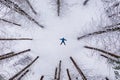 Winter aerial top view of man with blue jacket in the coniferous mountain forest. Spruce forest covered with snow. Man is lying in Royalty Free Stock Photo