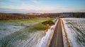 Winter Agricultural field under snow. Countryside road Aerial view. Lone pine tree near driveway