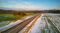 Winter Agricultural field under snow. Countryside road Aerial view. Lone pine tree near driveway