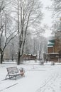 Winter alley, benches and footprints, wooden church under tall