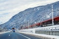 Winter alpine mountain highway and parallel railway road with intercity fast train and blue sky on background at bright Royalty Free Stock Photo