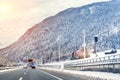 Winter alpine mountain highway and parallel railway road with intercity fast train and cloude sunset sky on background at cold day