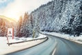 Winter alpine road curve landscape with forest, mountains and blue sky on background at bright cold sunny day. Car trip