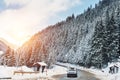 Winter alpine road curve landscape with forest, mountains and blue sky on background at bright cold sunny day. Car trip family