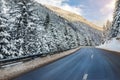 Winter alpine road curve landscape with forest, mountains and blue sky on background at bright cold sunny day. Car trip