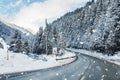 Winter alpine road curve landscape with forest, mountains and blue sky on background at bright cold twilight time. Car