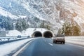 Winter alpine road landscape with tunnel, forest, mountains and blue sky on background at bright cold sunny day. Car Royalty Free Stock Photo