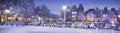 Winter in Amsterdam with snow. Panorama with bicycles, bridge, canal, old houses at night