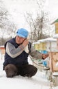 Winter on the apiary. Beekeeper winter monitors the status of bees in the hive. Winter bees in the hives in the yard.