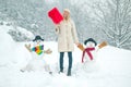 Winter background with snowflakes and snowman. Girl playing with snowman in winter park. Winter woman. Royalty Free Stock Photo