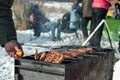 Winter barbecue outdoors, grill steak and fork with meat over hot coals, male hand cooking a BBQ at camping cookout Royalty Free Stock Photo