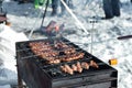 Winter barbecue outdoors, grill steak and fork with meat over hot coals in a BBQ at campside cookout, camping lifestyle Royalty Free Stock Photo