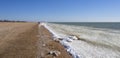 Winter beach of the sea with frozen sand and ice blocks and snow in the water. Snow-icy Cold dunes along the seashore. In the Royalty Free Stock Photo