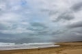 Winter beach with a storm brewing out to sea - two people walk in distance with a dog and the waves crash and foam - RedHead beach