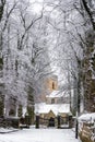 Winter a beautiful village church scene deep snow fall on roof trees lining driveway snowfall settled iron gates stone wall in tow Royalty Free Stock Photo