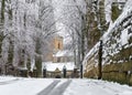 Winter a beautiful village church scene deep snow fall on roof trees lining driveway snowfall settled iron gates stone wall in tow Royalty Free Stock Photo