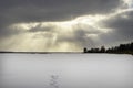 A winter blizzard is coming. Sunset over the frozen lake or river, forest. Footsteps, footprint tracks on the snow Royalty Free Stock Photo