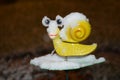 Winter blur background. Snow-cowered snail toy