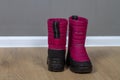 Winter boots snowboots dark pink with black soles on the floor in the room