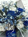 Winter bouquet of white and blue flowers. Flowers bouquet including Blue roses covered with snow, cones, fir branches, cotton ball