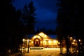 Winter Cabin at Night with Snow and Warm Glowing Lights Royalty Free Stock Photo