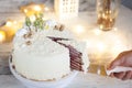 Winter cake with white cream decorated with gold hazelnuts, confectionery sprinkles and green New Year trees