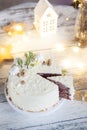 Winter cake with white cream decorated with gold hazelnuts, confectionery sprinkles and green New Year trees