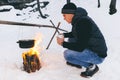 Winter camping, man warm up hands. Boiling water in pot. Wilderness and snow. Witnter time Royalty Free Stock Photo