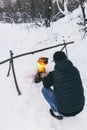 Winter camping, man warm up hands. Boiling water in pot. Wilderness and snow. Witnter time Royalty Free Stock Photo