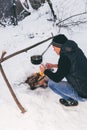 Winter camping, man warm up hands. Boiling water in pot. Wilderness and snow. Witnter time Royalty Free Stock Photo