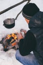 Winter camping, man warm up hands. Boiling water in pot. Wilderness and snow. Witnter time Royalty Free Stock Photo