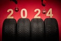 Winter car tires,wheels service, mechanics with christmas tree ball,new year 2024 red background Royalty Free Stock Photo