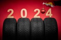 Winter car tires service and hand of mechanic with wrench and christmas ball, text 2024 happy new year on red background Royalty Free Stock Photo