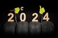 Winter car tires service and thumbs up hands of mechanic and text 2024 happy new year on black background Royalty Free Stock Photo