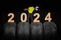 Winter car tires service and thumbs up hands of mechanic and text 2024 happy new year on black background Royalty Free Stock Photo