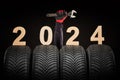 Winter car tires service and thumbs up hands of mechanic and text 2024 happy new year on black background Royalty Free Stock Photo