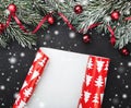 Winter card. Gift with red slack on a wrapping paper. Black stone background. With fir branches adorned with red balls Royalty Free Stock Photo