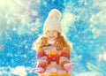 Winter cheerful little child playing throws up snow