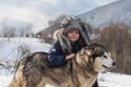 Winter childhood. Child embraced husky dog. Adorable little boy child with husky dog having fun on winter day. Royalty Free Stock Photo