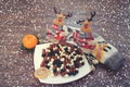 Winter Christmas composition. Coffee beans in chocolate on a plate, toy deer, wool socks and a candle on a wooden background and s