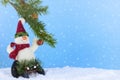 Winter Christmas scene of cute plush snowman playing on sled underneath a pine branch in artificial snow.