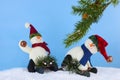 Winter Christmas scene of cute plush snowmen playing on sleds underneath a pine branch in artificial snow.