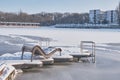 View of the frozen lake, beach and sun lounger covered with snow