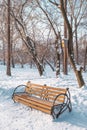 Winter city landscape. Wooden brown bench in a snowy park