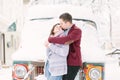 Winter city love. Happy young couple in warm sweaters having fun in winter city, hugging and standing near the old car Royalty Free Stock Photo