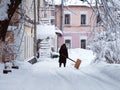 Winter in city. Small yard in town, covered with snow. A woman removes snow