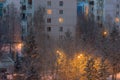 Winter cityscape of Russian Troitsk town. Trees in snow and residential buildings on street with warm light