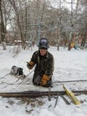 winter climber drilling the wall of the house against the background of snow-covered trees