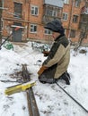 winter climber drilling the wall of the house against the background of snow-covered trees Royalty Free Stock Photo